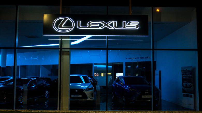 Lexus company logo on the outside of a Lexus dealership, shot at night.