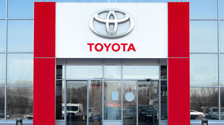The entrance to a Toyota dealership with a large silver and red Toyota logo above the doors.