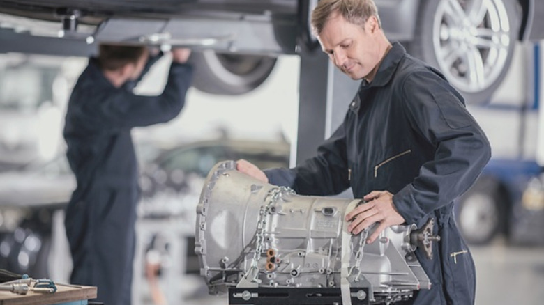 A technician working on a transmission that's already been pulled out of a car