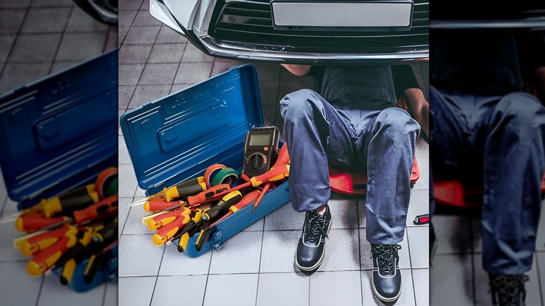 Man working under car with blue Acshio metal tool box next to him