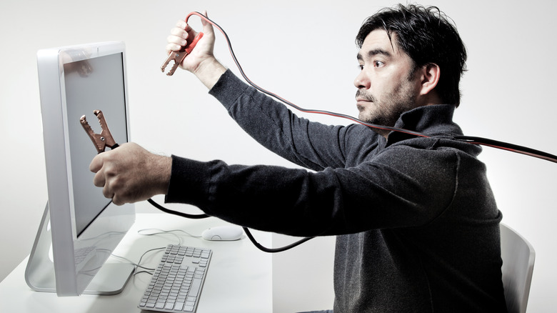 Holding jumper cables up to a computer
