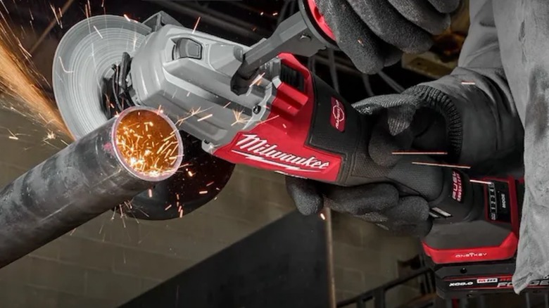 Person cutting metal pipe with Milwaukee Dual-Trigger Braking Grinder