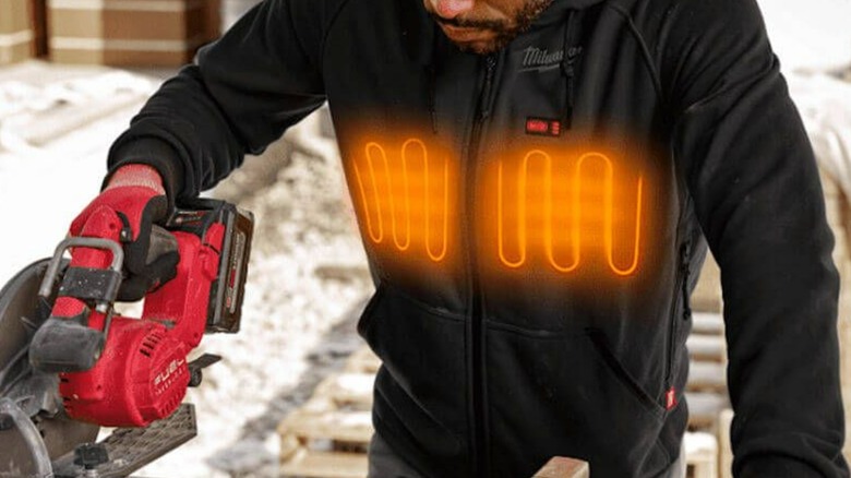 A person wearing a Milwaukee heated hoodie while working.