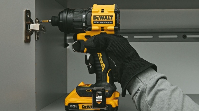 A person using the DeWalt 20V Max Multi-Head Drill/Driver to affix a hinge