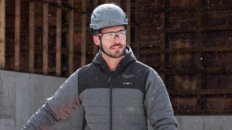 Man wearing Milwaukee jacket and helmet in snow