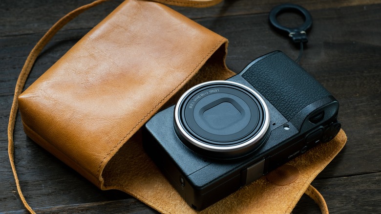 Compact camera sitting outside of leather bag