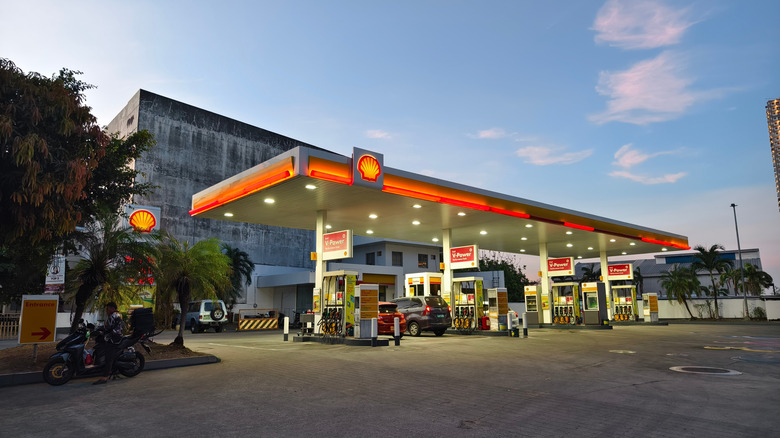 Shell gas station in service, as viewed from sidewalk during sunset