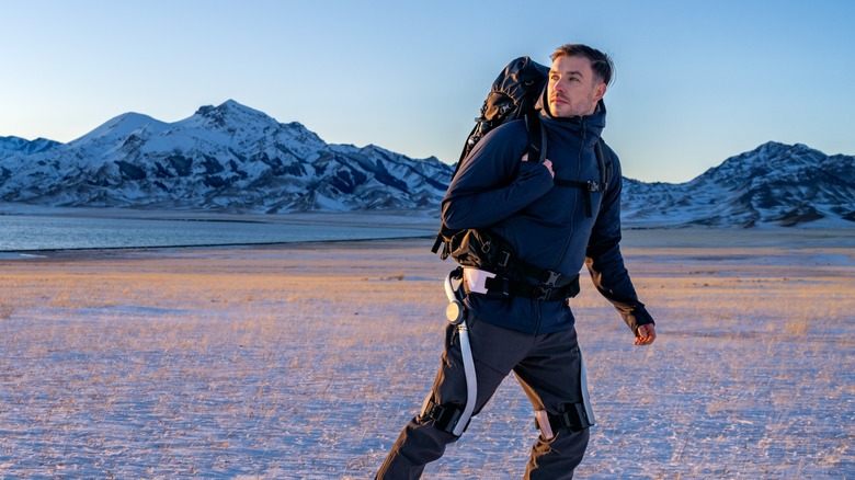 A backpacker walks near a mountain with a Hypershell X