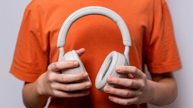 Person holding a pair of Sony WH-1000XM5 headphones