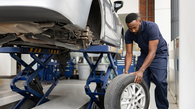 Mechanic removed a tire from a vehicle on a jack.