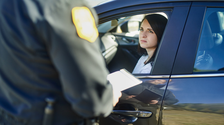 Traffic officer writes a person a ticket at a checkpoint