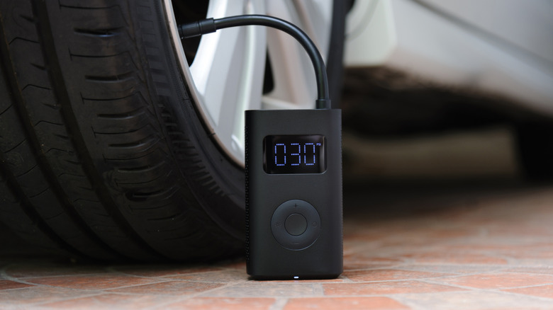 A portable air compressor filling up air inside a car's tire