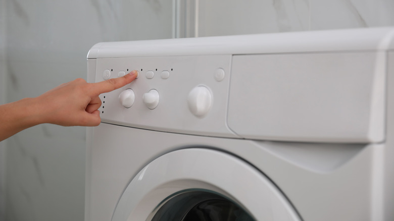 A person pressing a button on the washing machine