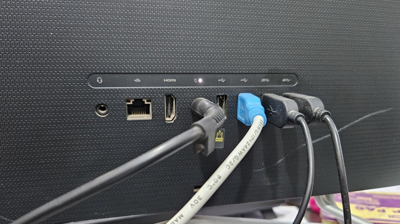 Multiple plugs, including USB cables, inserted into the backside of a monitor