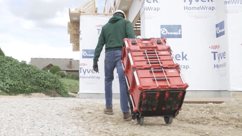 Man in construction hat pulls Milwaukee Packout modular tool storage system behind him