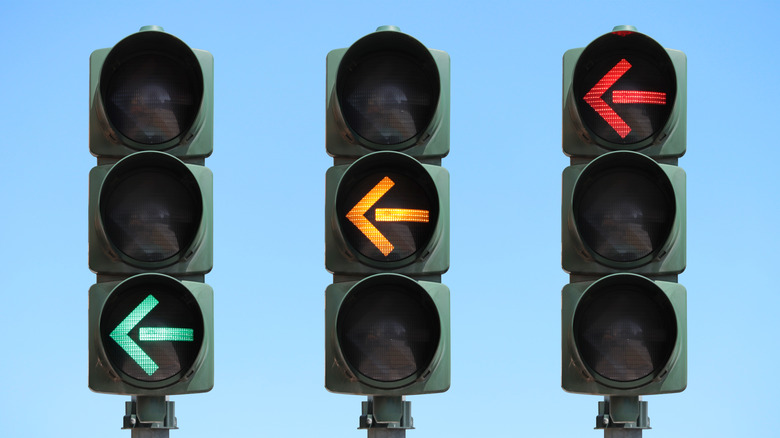 Three traffic lights each on a different color against blue sky