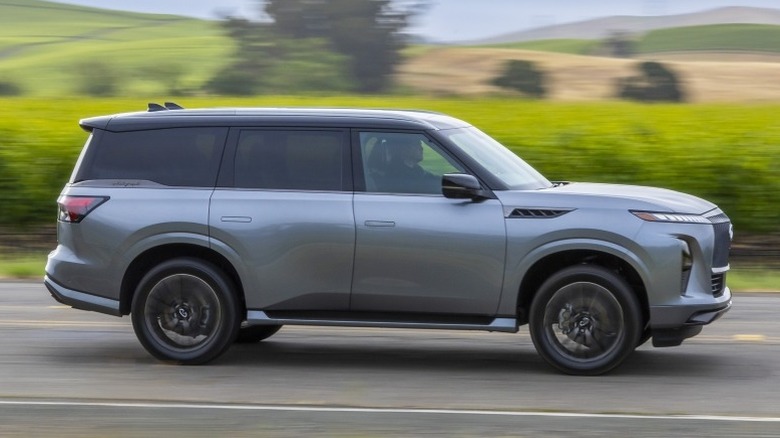 Side profile of a 2025 Infiniti QX80 driving on a road