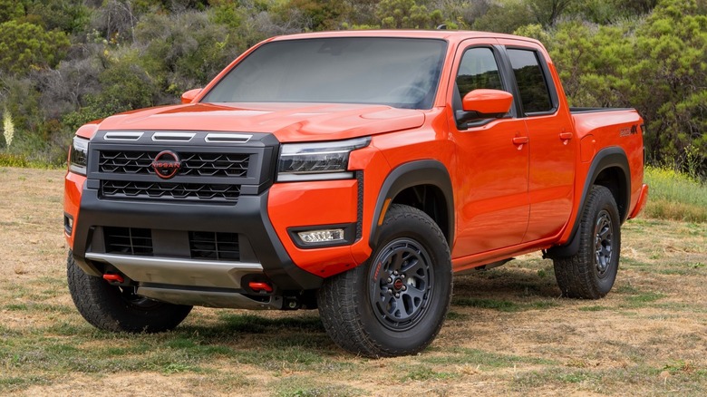 2025 Nissan Frontier PRO-4X parked on a grassy field with trees in the background