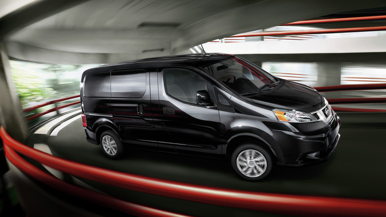 Black Nissan NV200 van driving in parking garage