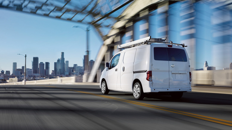 White Nissan NV200 van driving on bridge