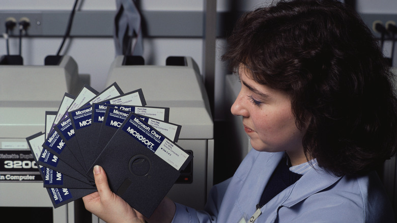 A technician fanning out multiple floppy disks in one hand