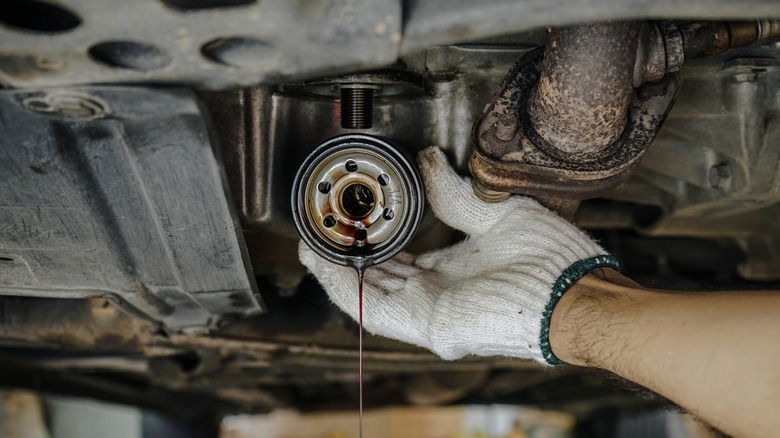 A person removing a car's oil filter