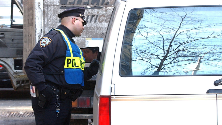 A New York policeman talking to the driver of a white van through the window.