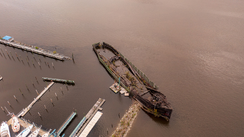 An aerial drone view over a wooden ship, partially sunken in Cornwall on the Hudson River, New York City.