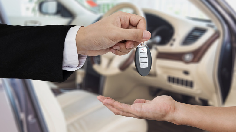 Dealership employee handing over car keys to a buyer
