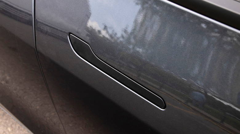 An image of a dark grey Tesla with a flush door handle