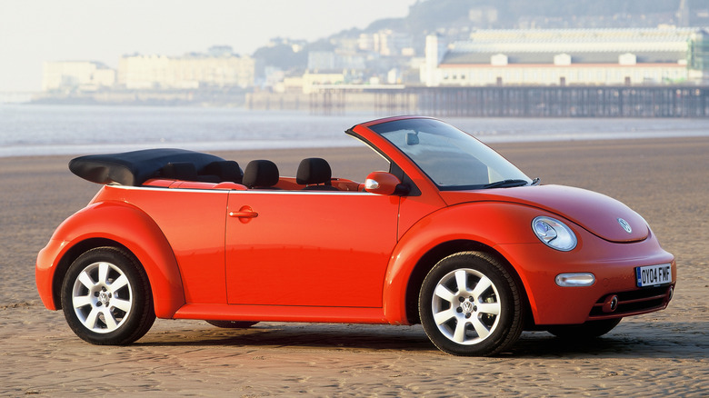 Red Volkswagen New Beetle Cabriolet seen from right parked on a beach
