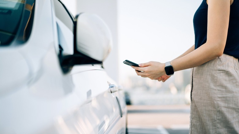 A person using their phone to unclock their car