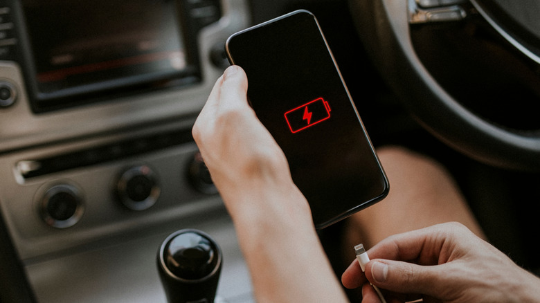 A man plugging the cable into a phone showing low battery icon