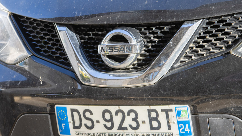A close-up of the front end of a dirty Nissan with a French number plate