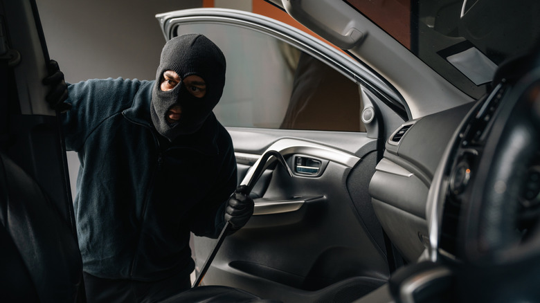 A thief looking around inside a broken-into vehicle.