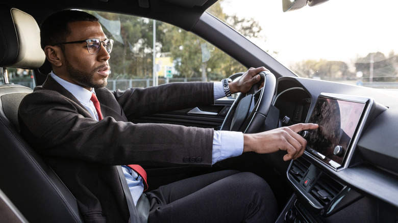 A man using his touchscreen to access features in his car.