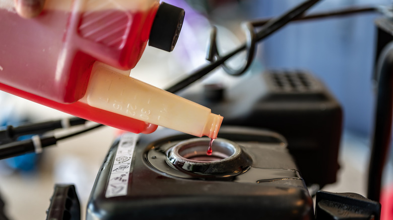 A person pouring fuel stabilizer into a gas tank.