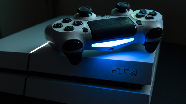 A Glacier White PS4 Pro edition with a dual shock controller on top lit up in blue.