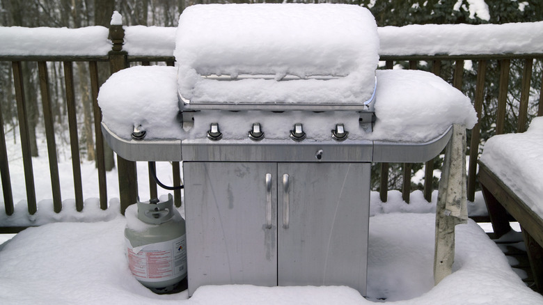 A propane grill and tank outside in the snow
