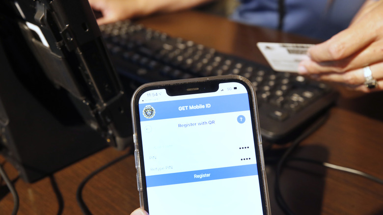 A Utah Department of Motor Vehicle employee helps a man convert his physical driver licenses to official digital versions