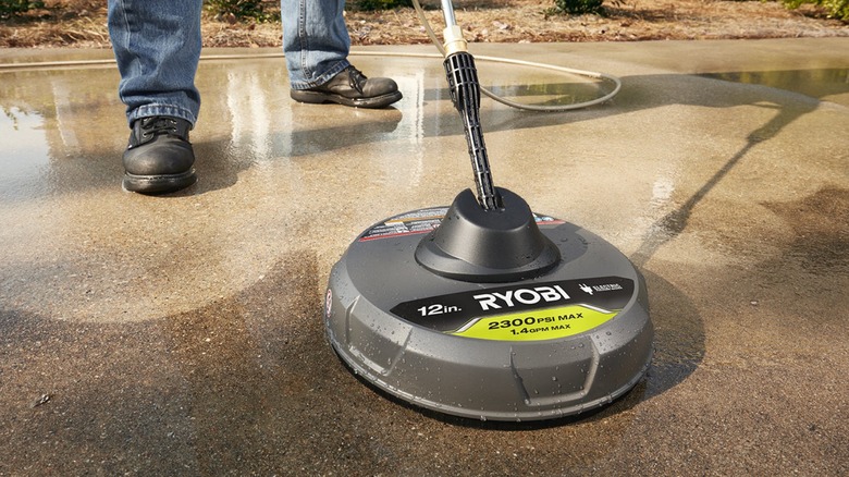 Person cleaning driveway with Ryobi surface cleaner