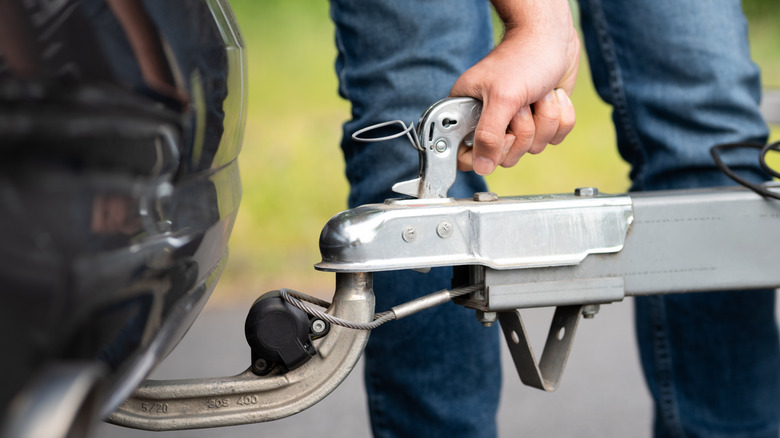 A person attaching a trailer to a ball hitch.