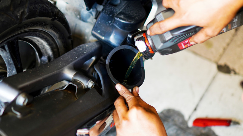 A mechanic is changing new engine oil into a motorcycle engine