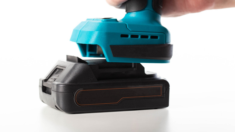 An unbranded power tool battery on a teal power tool, close-up shot