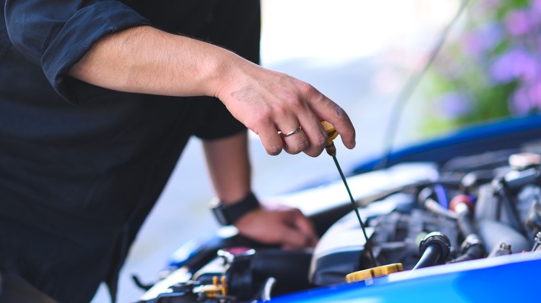 Person pulling the dipstick from the engine bay