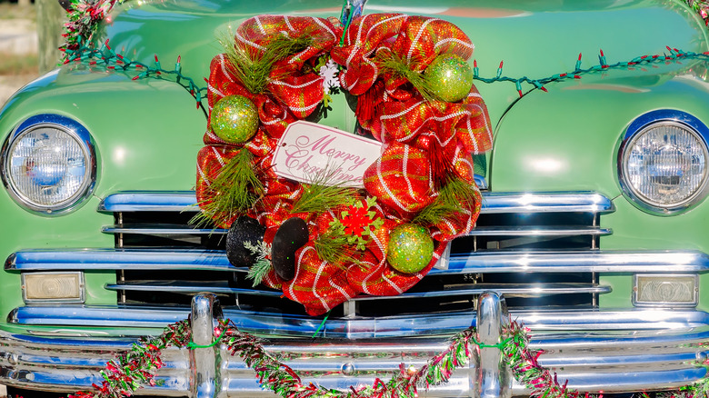 Old green car with christmas wreath attached to front