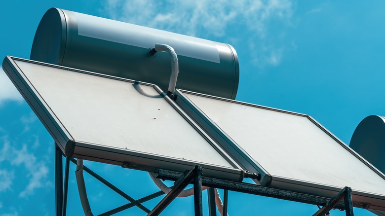 Close-up of rooftop solar water heater system under a clear blue sky.