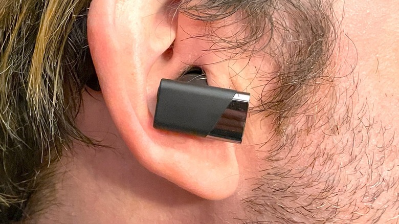 Status Pro X wireless earbuds in front of the open charging case.