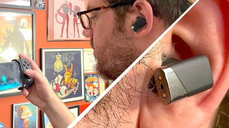 Status Pro X earbuds in a person's left ear as they hold an Android phone in a grip-style controller.