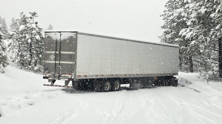 Semi-truck stuck in snow across roadway